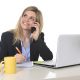 happy Caucasian blond business woman working talking on mobile phone at office computer desk